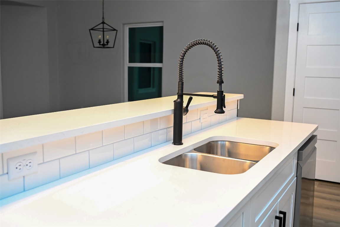 516 North Hackberry Avenue Luling, TX 78648 - Photo 23 of 36 Kitchen view of hanging light fixtures, white cabinetry, stainless steel dishwasher, light stone counters, and dark wood-style floors