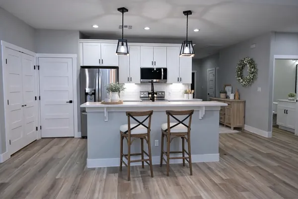 a kitchen with stainless steel appliances a dining table chairs refrigerator and microwave