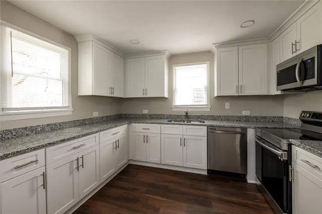a kitchen with stainless steel appliances granite countertop a sink and cabinets with wooden floor