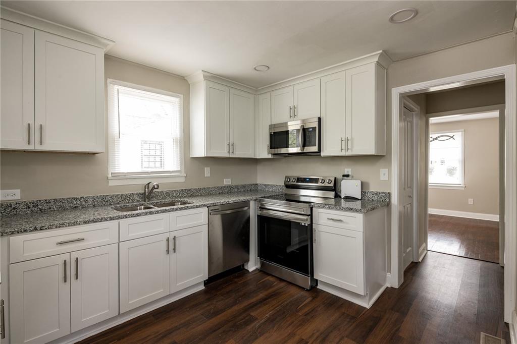 1854 Broadwell Street Southwest Atlanta, GA 30310 - Photo 16 of 18 a kitchen with stainless steel appliances granite countertop a sink and cabinets with wooden floor