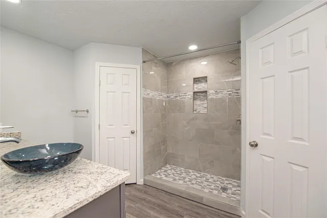 a bathroom with a granite countertop sink a mirror and shower
