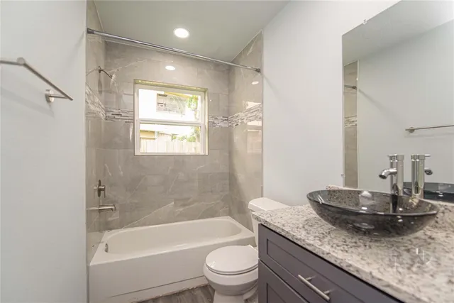 a bathroom with a granite countertop sink a toilet and shower