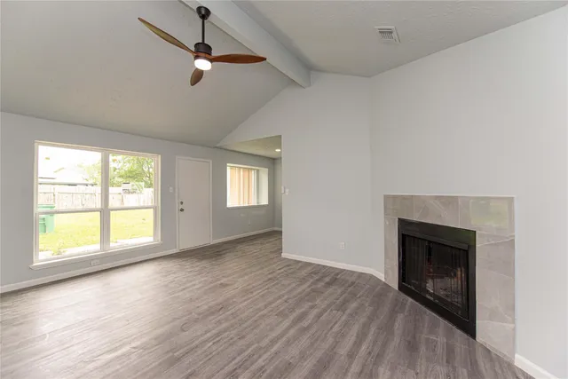 a view of an empty room with a fireplace and wooden floor