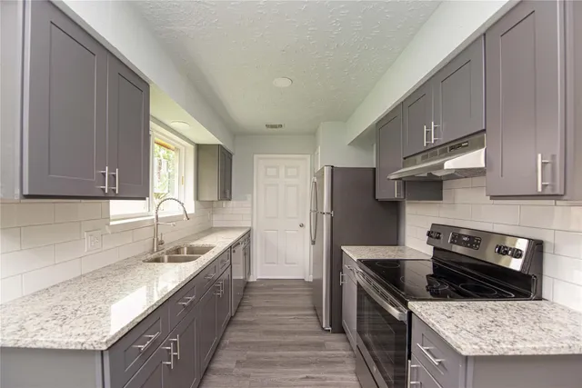 a kitchen with stainless steel appliances granite countertop a sink stove and refrigerator