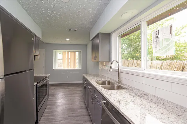 a large kitchen with kitchen island a large window appliances and cabinets