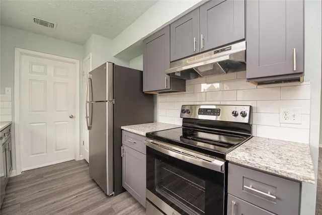 a kitchen with stainless steel appliances granite countertop a refrigerator stove and cabinets