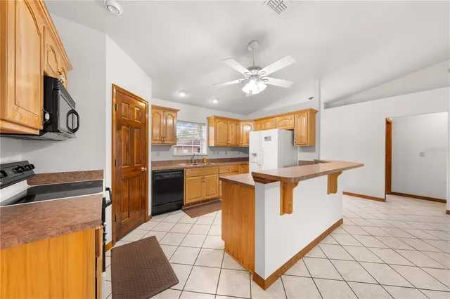 a kitchen with stainless steel appliances granite countertop a refrigerator a sink dishwasher a dining table and chairs with wooden floor