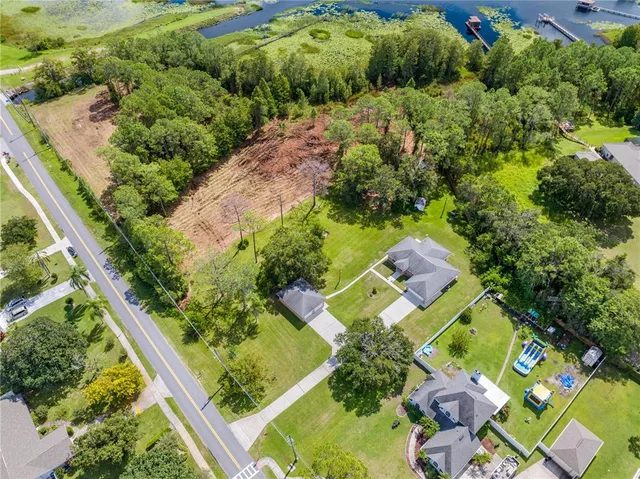an aerial view of residential house with outdoor space and trees all around