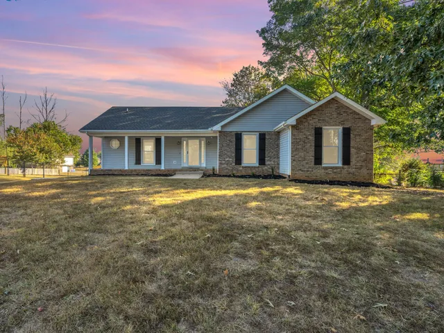 a front view of a house with a yard and trees