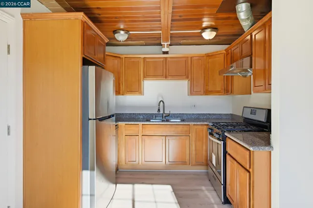 a kitchen with granite countertop a sink and a refrigerator