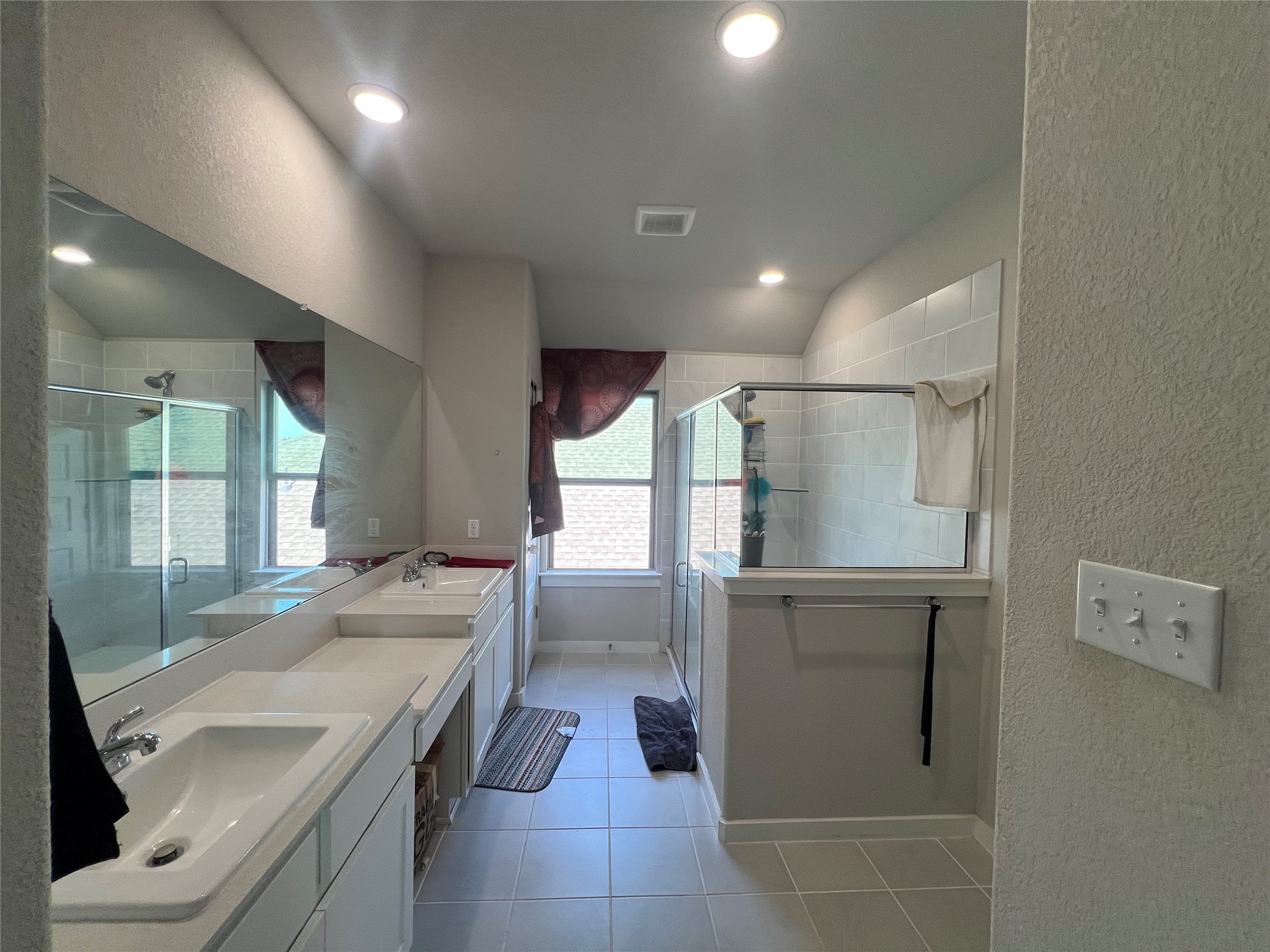 172 Coppers Way Elgin, TX 78621 - Photo 9 of 27 Tiled flooring runs throughout this primary bathroom featuring a dual vanity design and glass shower enclosure.