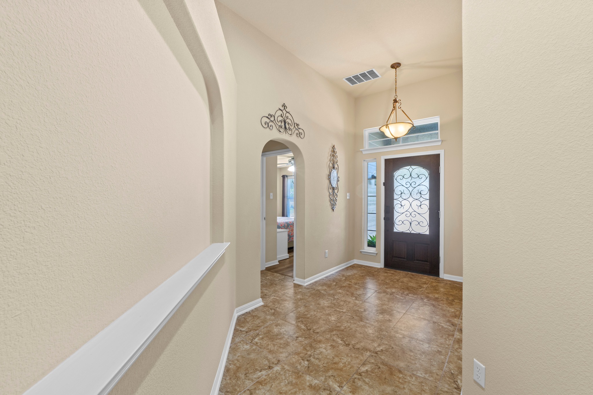 20525 Jackies Ranch Boulevard Pflugerville, TX 78660 - Photo 16 of 27 Entrance foyer with arched walkways, a textured wall, and a high ceiling with chandelier