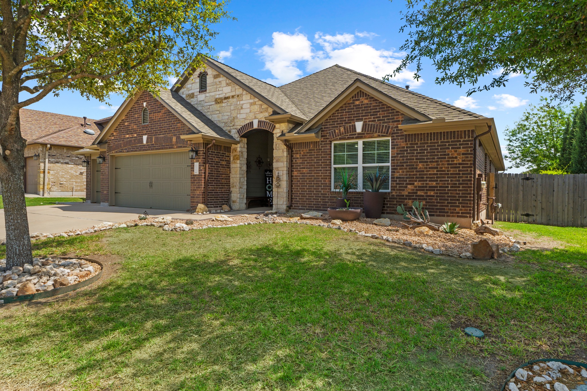 20525 Jackies Ranch Boulevard Pflugerville, TX 78660 - Photo 2 of 27 View of front of property with stone siding, brick siding, an attached garage, wide concrete driveway.