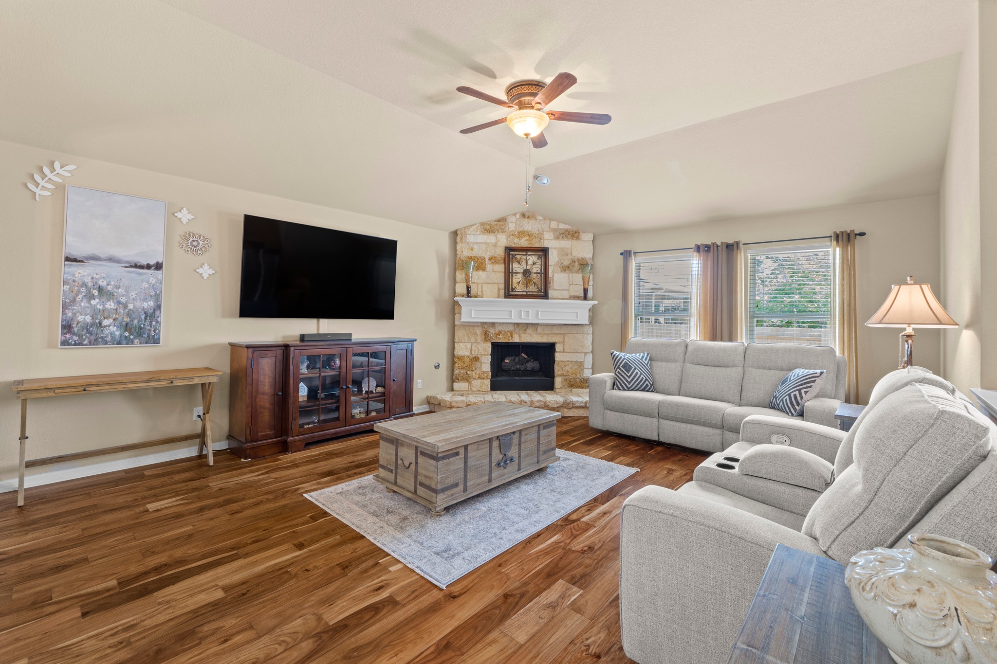20525 Jackies Ranch Boulevard Pflugerville, TX 78660 - Photo 4 of 27 Living area with Acacia wood engineered flooring, vaulted ceiling, a ceiling fan with light, and a gas fireplace with logs and embers