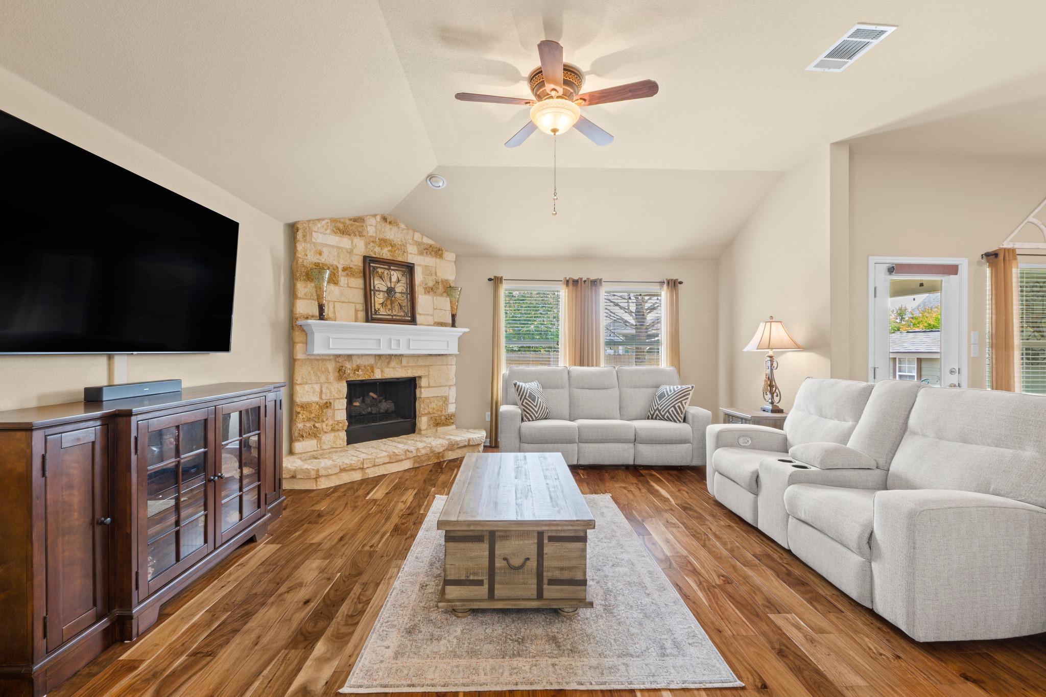 20525 Jackies Ranch Boulevard Pflugerville, TX 78660 - Photo 5 of 27 Living area with Acacia wood engineered flooring, vaulted ceiling, a ceiling fan with light, and a gas fireplace with logs and embers