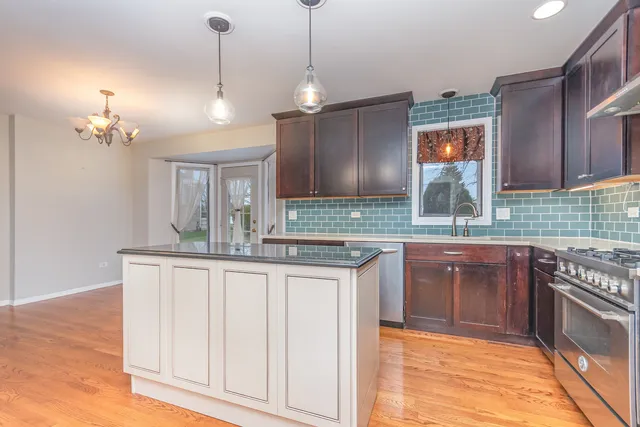 a kitchen with kitchen island granite countertop a sink cabinets and stainless steel appliances