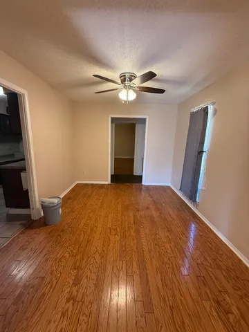 a view of empty room with wooden floor and fan