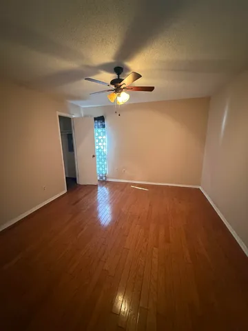 a view of an empty room with window and wooden floor