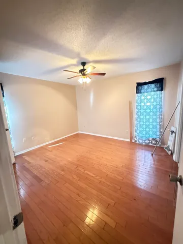 an empty room with wooden floor and windows