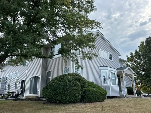 a front view of a house with a garden and tree