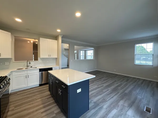 a large kitchen with stainless steel appliances granite countertop a sink dishwasher a stove and a refrigerator with wooden floor