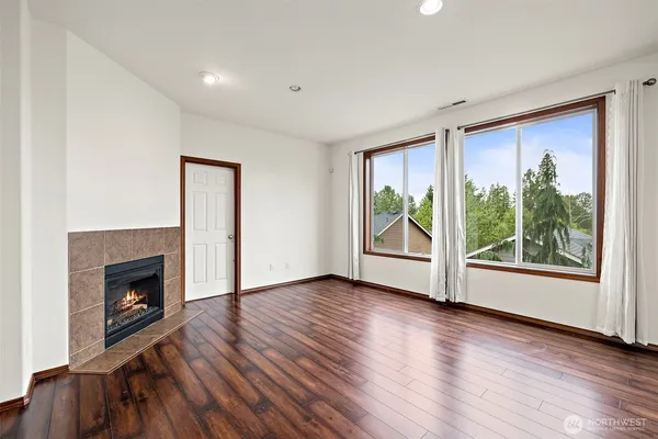 an empty room with wooden floor fireplace and windows