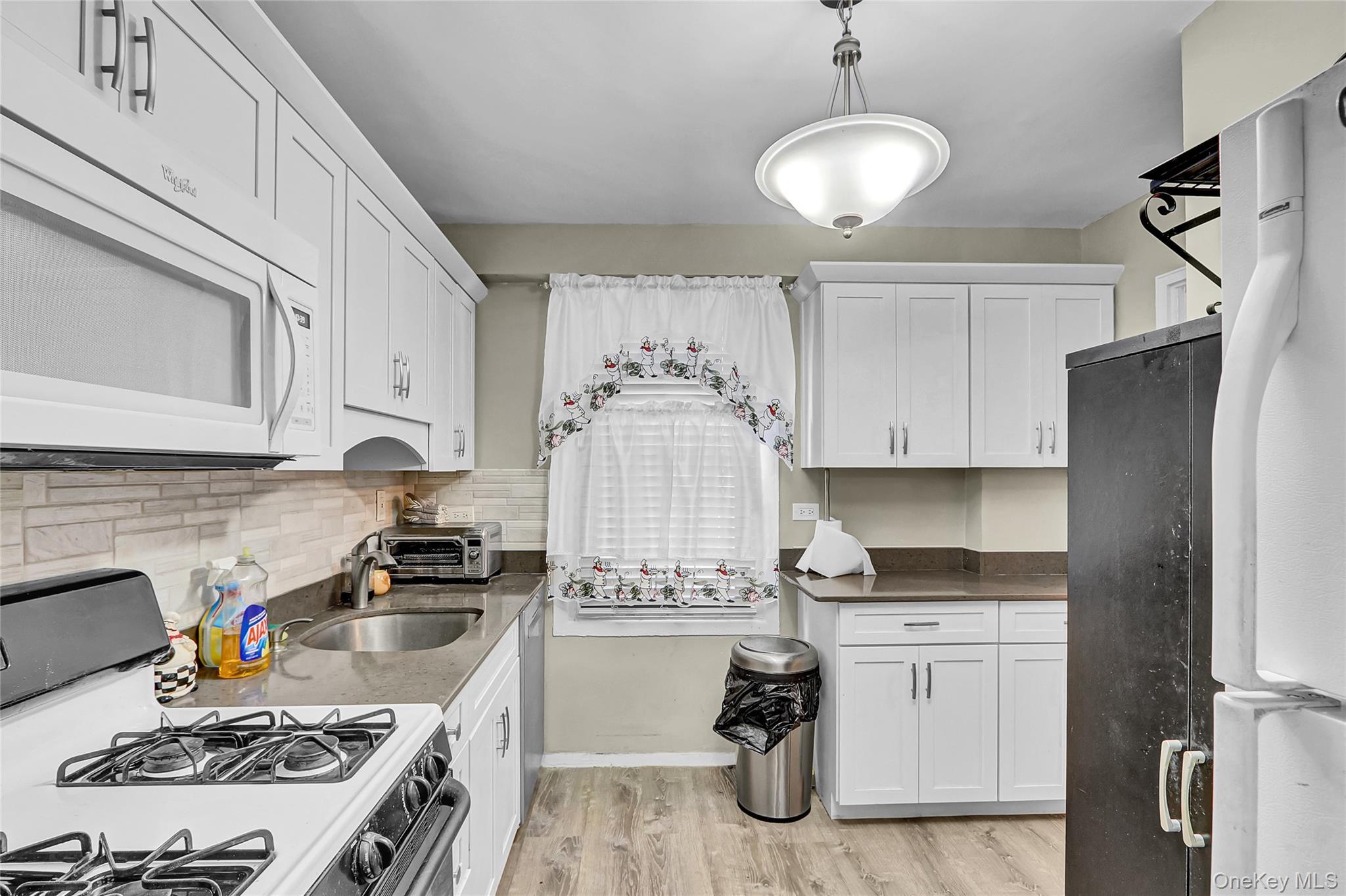 123-40 83rd Avenue, Unit 6D Queens, NY 11415 - Photo 4 of 14 Kitchen with white appliances, white cabinets, light wood-style flooring, dark stone counters, and pendant lighting