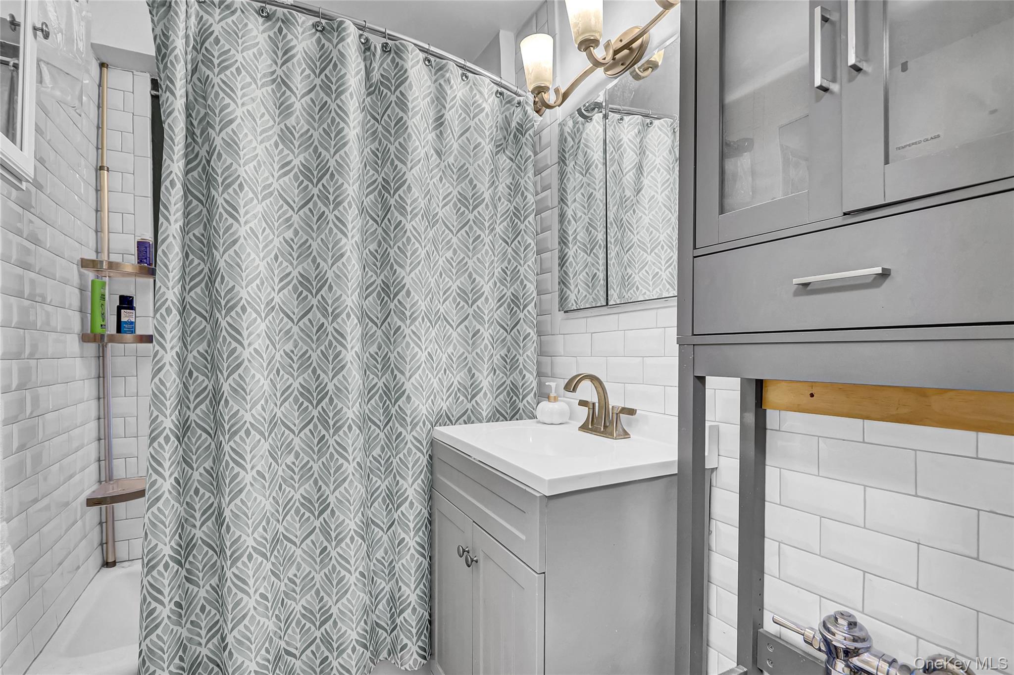 123-40 83rd Avenue, Unit 6D Queens, NY 11415 - Photo 9 of 14 Bathroom with vanity, tile walls, shower / bath combination with curtain, and a chandelier