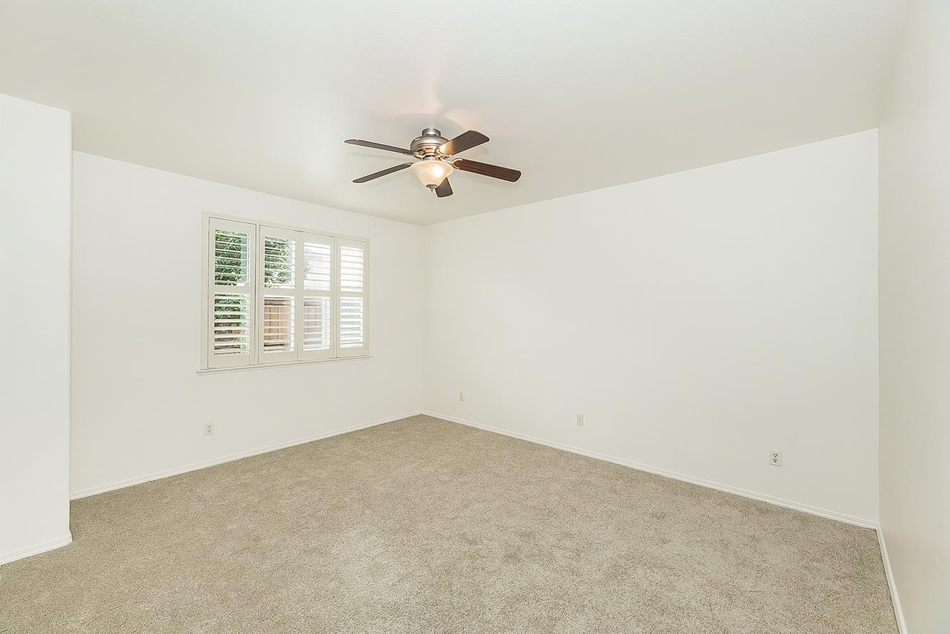 an empty room with a window and a ceiling fan