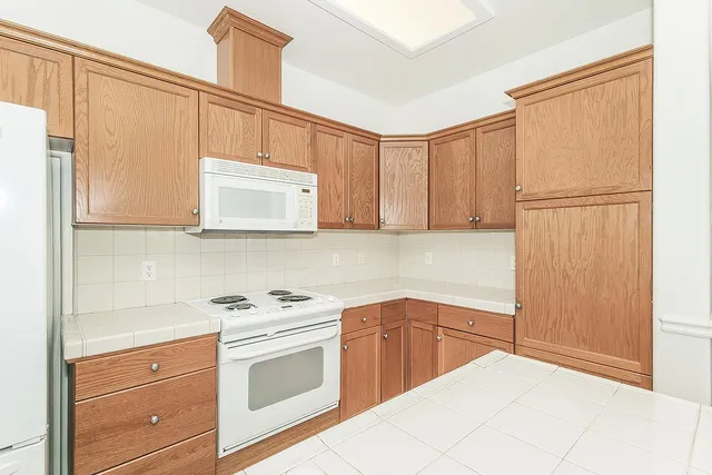 a kitchen with white cabinets and white appliances