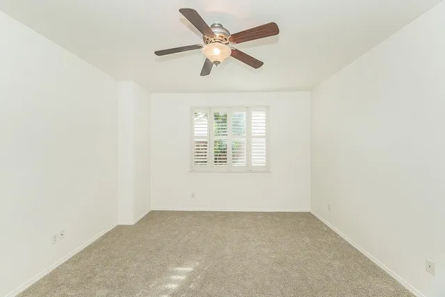 an empty room with a window and a ceiling fan