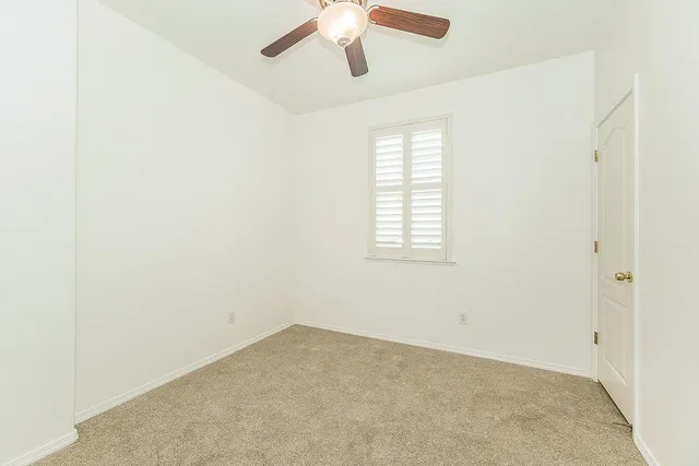 an empty room with a window and a ceiling fan