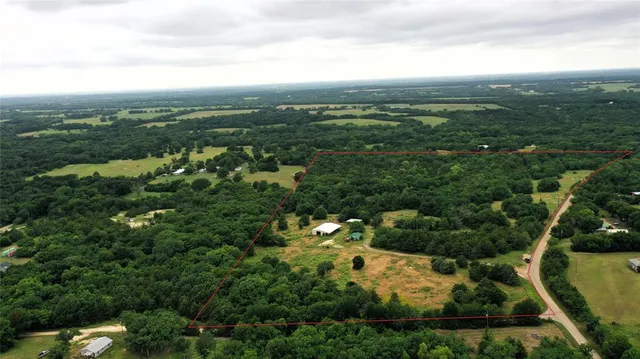 an aerial view of residential houses with outdoor space and trees