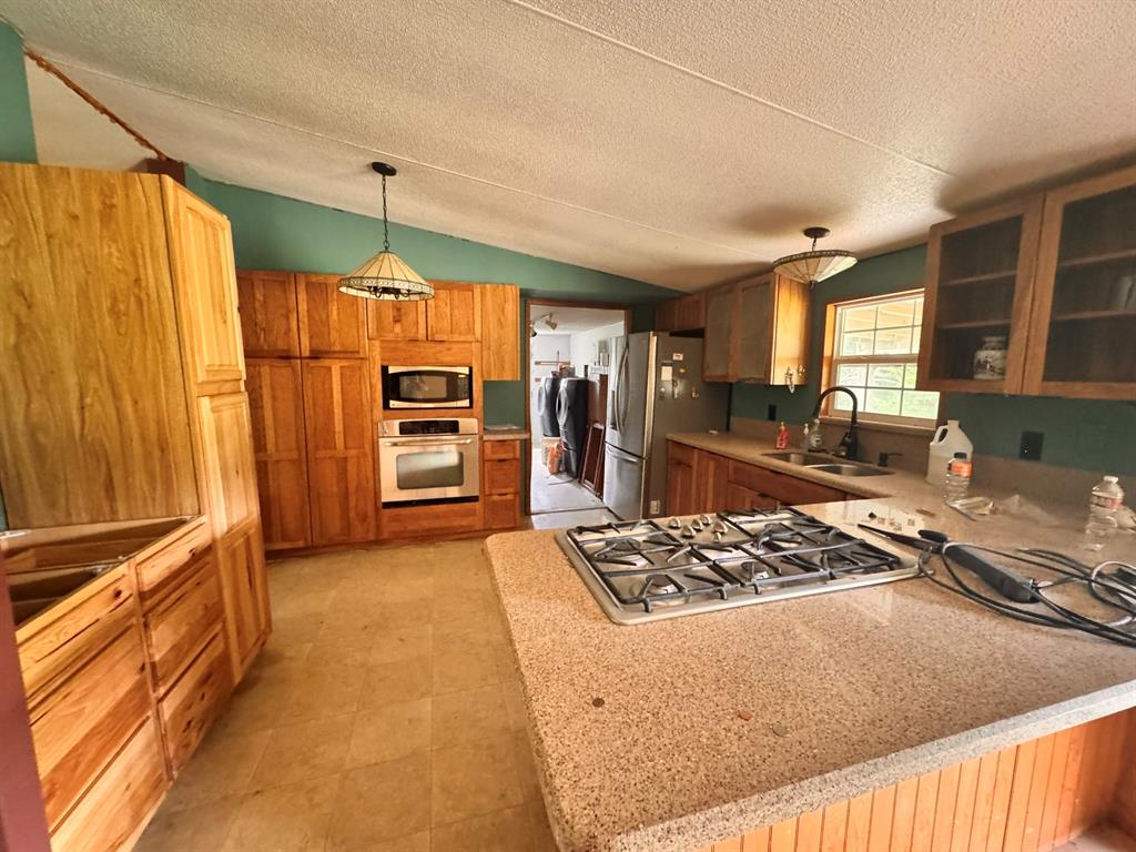 1980 County Road 3040 Bonham, TX 75418 - Photo 15 of 34 a kitchen with stainless steel appliances granite countertop a stove refrigerator and cabinets