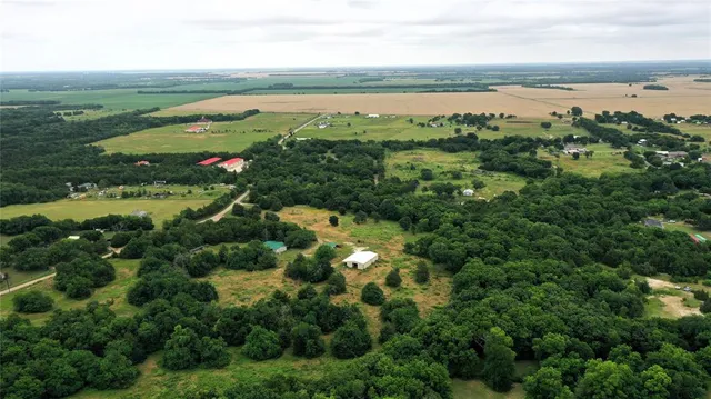 an aerial view of residential houses with outdoor space and trees