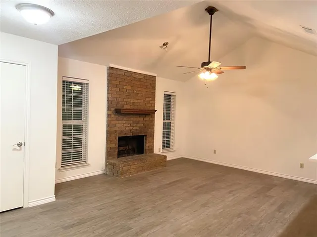 a view of a livingroom with a fireplace a ceiling fan and windows