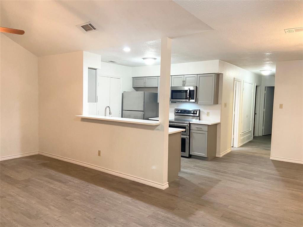 2121 Stone Moss Lane Grapevine, TX 76051 - Photo 3 of 17 a kitchen with white cabinets and stainless steel appliances