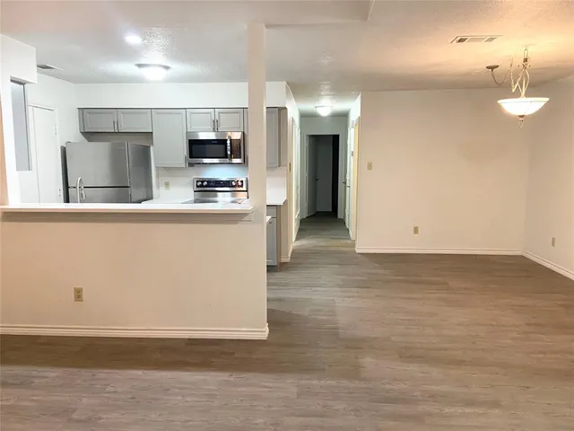 a view of a kitchen with stainless steel appliances wooden floor and living room view