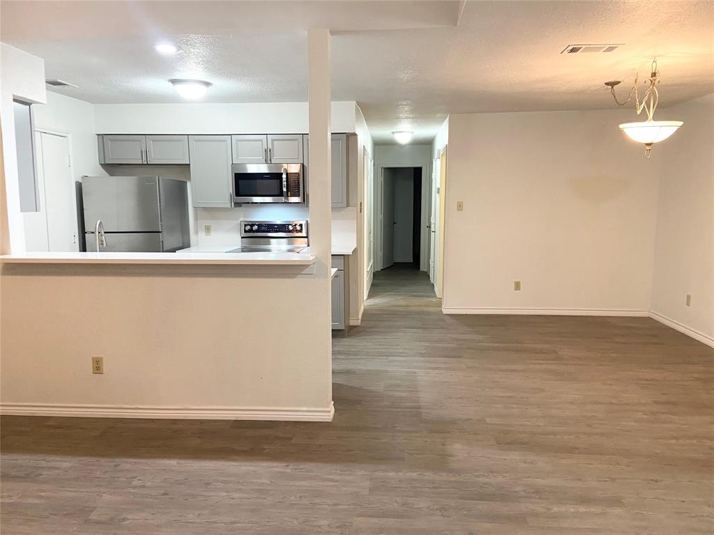 2121 Stone Moss Lane Grapevine, TX 76051 - Photo 5 of 17 a view of a kitchen with stainless steel appliances wooden floor and living room view