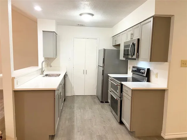 a kitchen with stainless steel appliances a sink stove refrigerator and cabinets