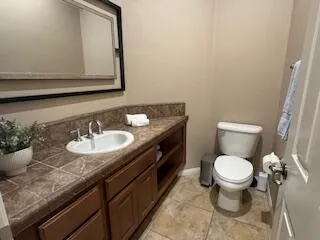 a bathroom with a granite countertop sink and a toilet