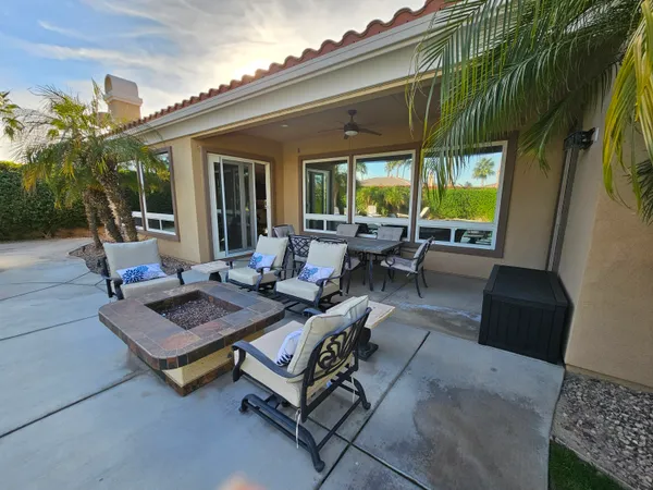 a view of a patio with couches table and chairs with wooden floor and fence