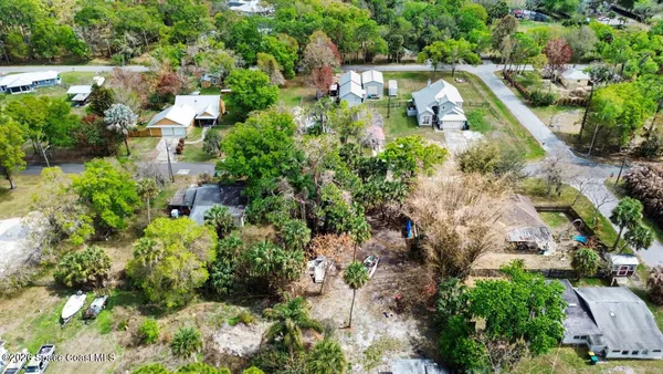 an aerial view of residential houses with outdoor space and trees all around