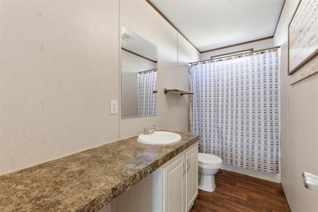1409 South Drive Venus, TX 76084 - Photo 20 of 31 a bathroom with a granite countertop toilet a sink and a shower