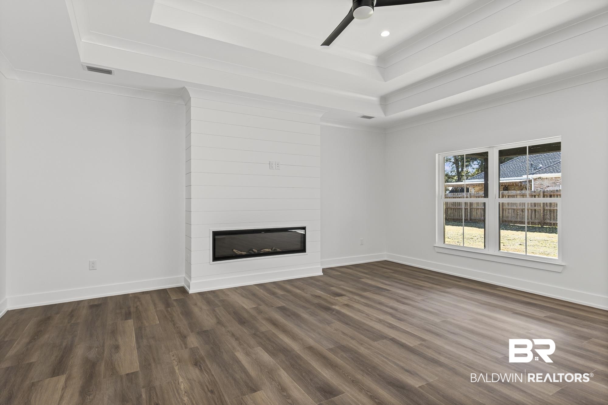 10180 Pineview Drive Foley, AL 36535 - Photo 11 of 47 Unfurnished living room featuring crown molding, a fireplace, a tray ceiling, dark wood finished floors, and ceiling fan