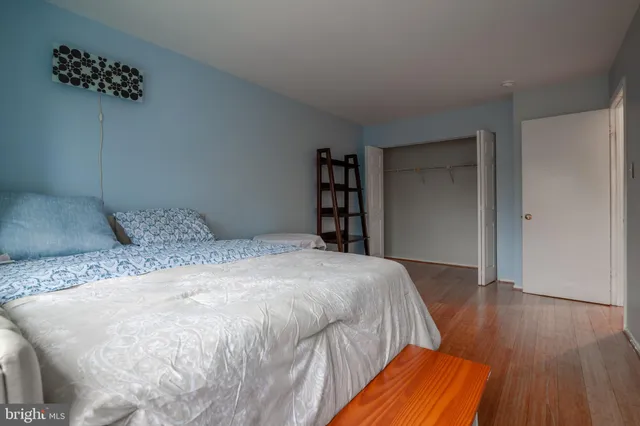 a spacious bedroom with a bed and wooden floor