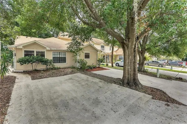a view of a house with a yard and large trees