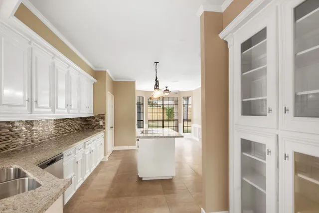 a kitchen with granite countertop a stove and white cabinets