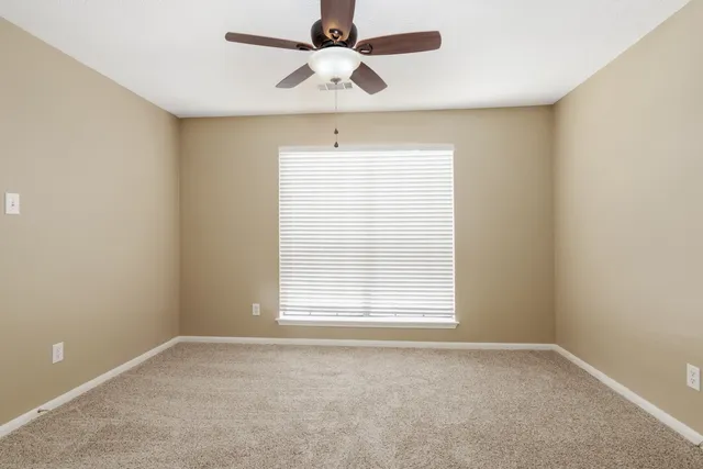 an empty room with a window and a fan