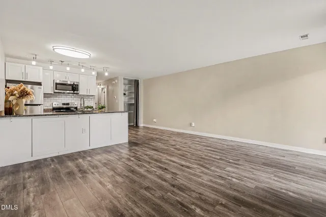 a view of an empty room with wooden floor and window